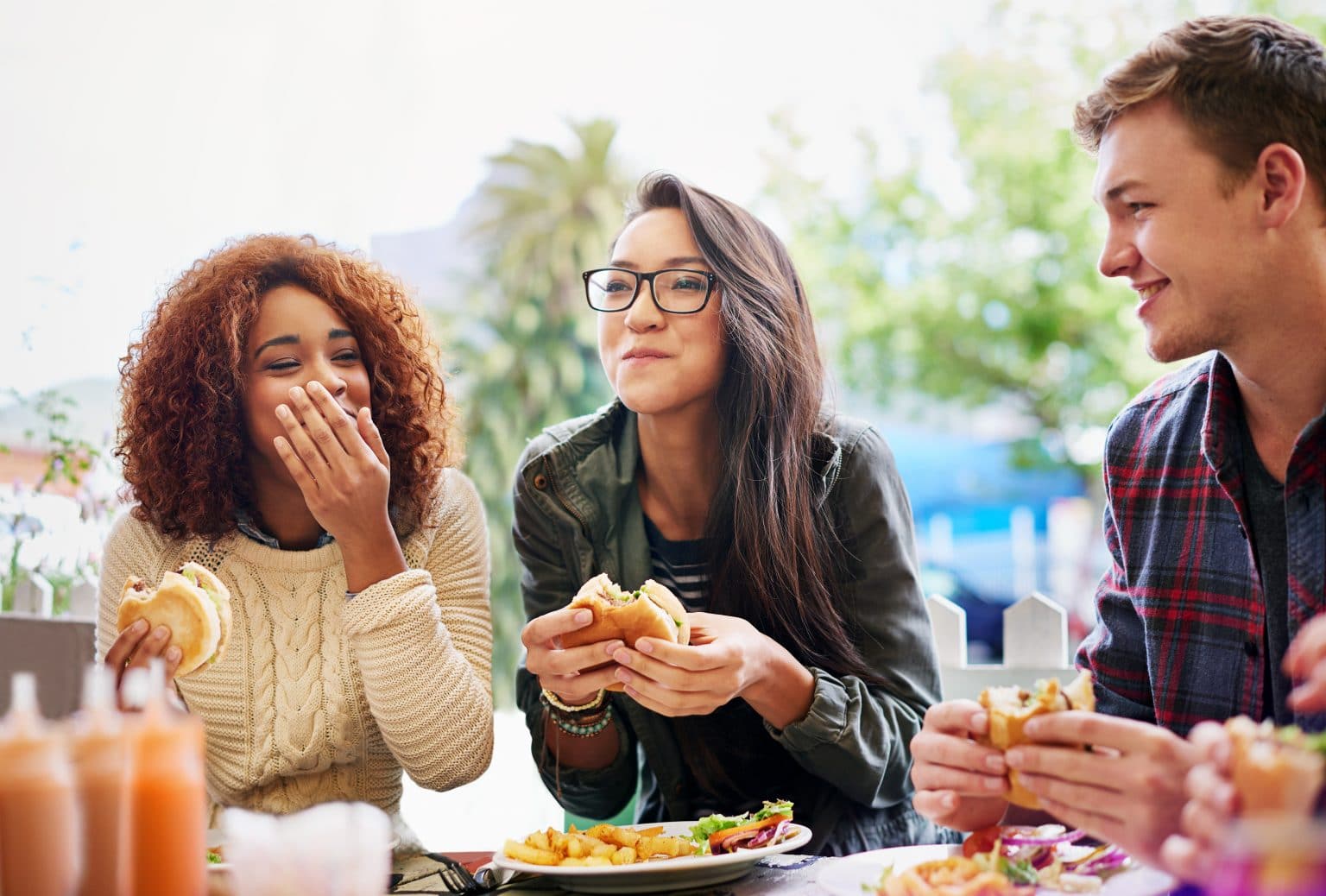 Group of friends happily eating burgers at a restaurant